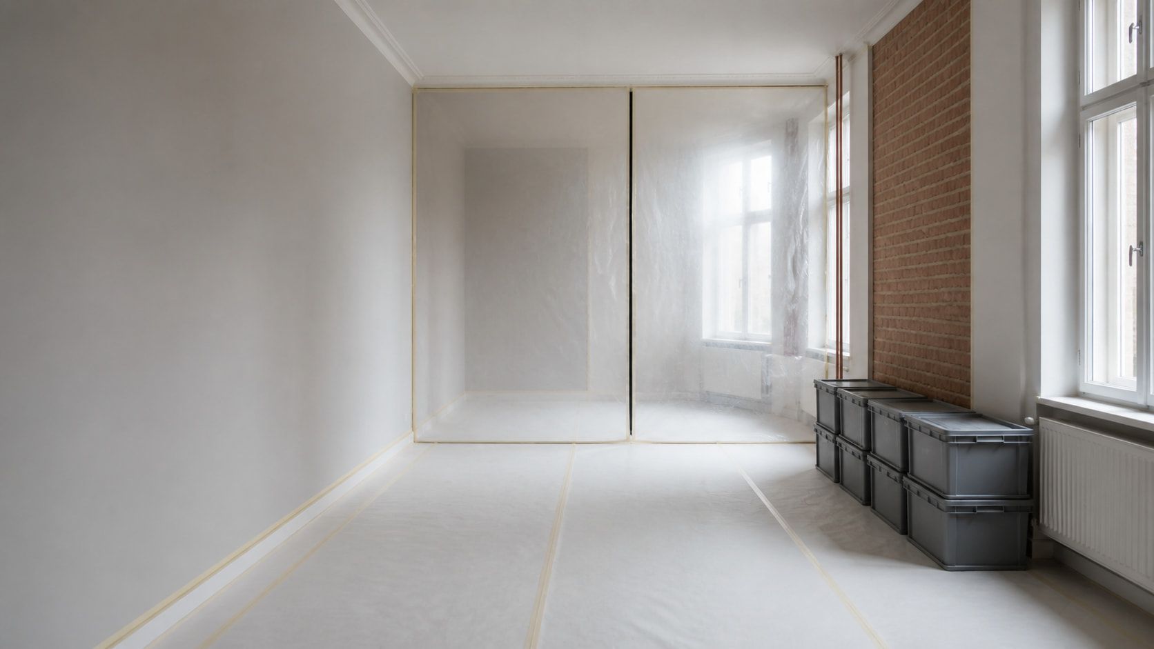 Bauleiter prüft Unterlagen in einer Wohnung, im Hintergrund abgeklebte Türöffnung und Staubschutz
