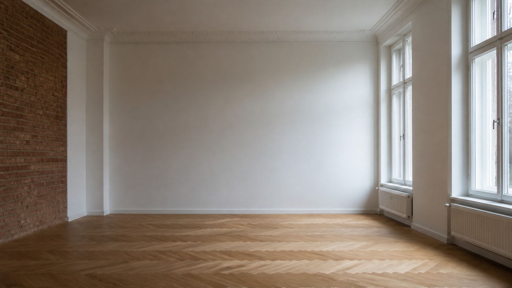 Sanierter Wohnraum in einem Kölner Bestandsgebäude: neu verputzte Wand, freigelegtes Mauerwerk und frisch verlegter Holzboden